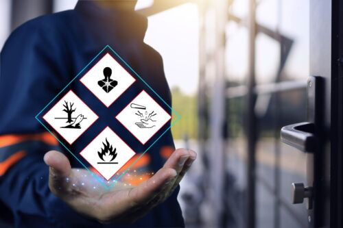 Warehouse personnel show warning signs of hazardous substances in hand, indicating preparedness in emergency situations and preparations to prevent potential dangers. MSDS and safety chemical concept. Visual concept for blog discussing the differences between Occupational Disease and Industrial Injuries.