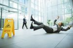 Businessman slipping on floor of office building - workers comp and personal injury concept
